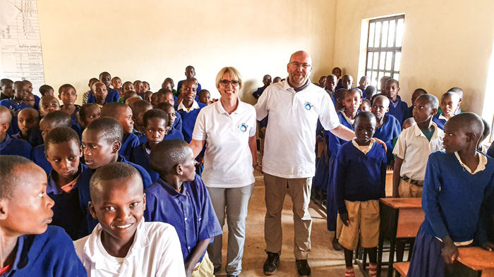 Ehepaar steht in Klassenraum in Malawi mit fröhlichen Kindern