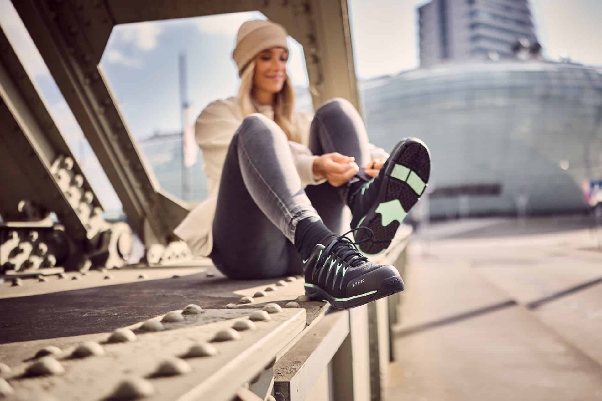 Frau in Damen-Sicherheitsschuhen sitzt auf einer Br&uuml;cke